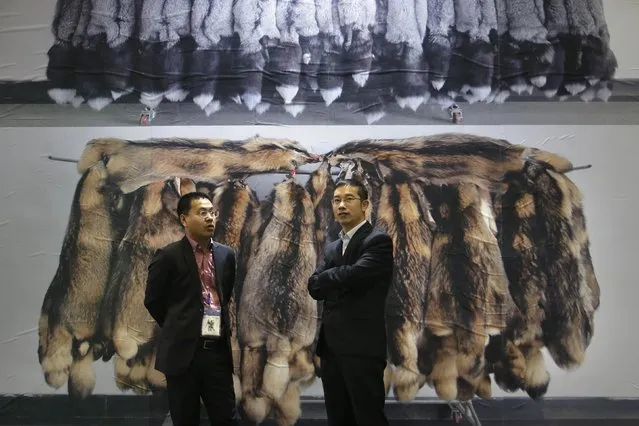 Exhibitors chat in front of a poster showing the fur of farmed fox (top) and of farmed raccoon at the 2015 China Fur and Leather Products Fair in Beijing, January 15, 2015. (Photo by Jason Lee/Reuters)