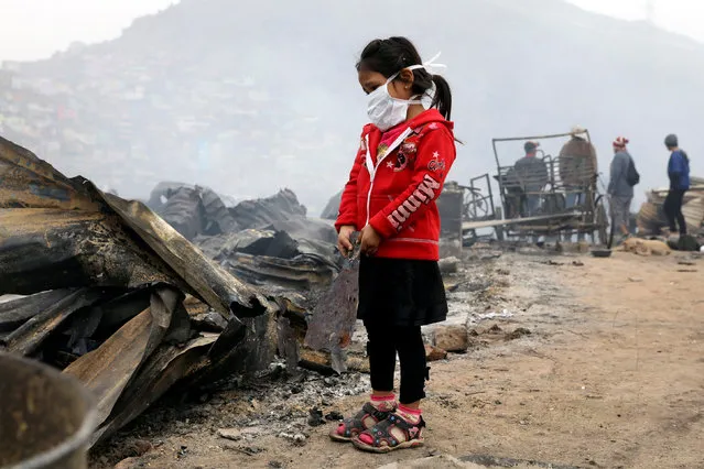 A child stands at the scene of a fire at 'Cantagallo' shanty town in Rimac district of Lima, Peru November 4, 2016. (Photo by Guadalupe Pardo/Reuters)