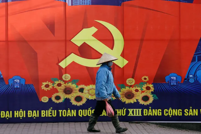A woman wearing a conical hat walks past a poster for the 13th national congress of the Vietnamese Communist party, which is due to start next week, in Hanoi, Vietnam on January 17, 2021. (Photo by Kham via Reuters)