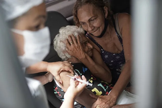 An elderly woman gets a shot of China's Sinovac CoronaVac vaccine as part of a priority COVID-19 vaccination program for the elderly at a drive-thru vaccination center in Rio de Janeiro, Brazil, Monday, February 1, 2021. (Photo by Silvia Izquierdo/AP Photo)