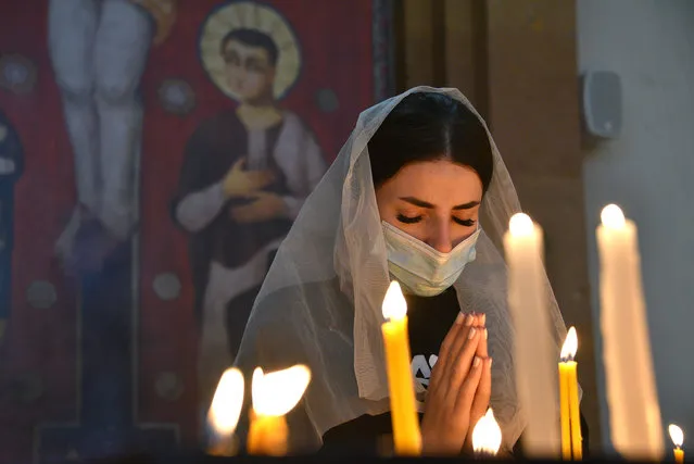 An Armenian woman, wearing a face mask, prays in a church in Yerevan on October 17, 2020, for Armenians killed during fighting over the breakaway region of Nagorno-Karabakh. Baku and Yerevan have for decades been locked in a simmering conflict over Nagorno-Karabakh, an ethnically Armenian region of Azerbaijan which broke away from Baku in a 1990s war that claimed the lives of some 30,000 people. The Caucasus neighbours have defied international calls to halt hostilities and accused the other of starting new clashes that began September 27 and have seen the heaviest fighting since a 1994 truce. (Photo by Karen Minasyan/AFP Photo)
