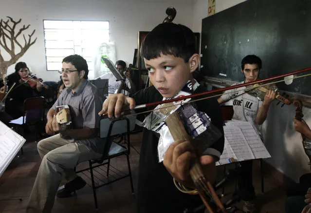 Director of the Orchestra of Recycled Instruments of Cateura, Favio Chavez (L, gray shirt), leads his music students during a rehearsal at the Vy'a Renda education center in Cateura, near Asuncion, May 8, 2013. (Photo by Jorge Adorno/Reuters)