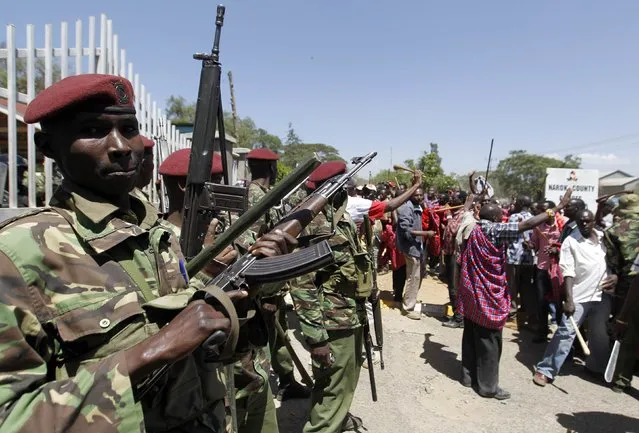 Riot policemen stand guard as they block residents chanting slogans during protests to oust Narok county Governor Samuel Tunai in Narok, Kenya, January 26, 2015. (Photo by Thomas Mukoya/Reuters)