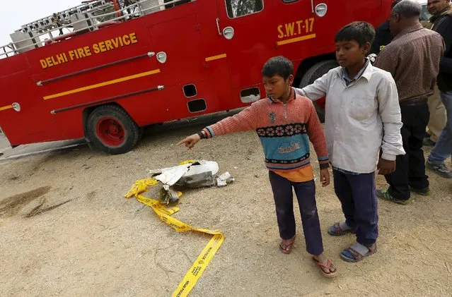 Boys stand next to the wreckage of a crashed aircraft on the outskirts of New Delhi, India, December 22, 2015. The aircraft crashed into a wall and burst into flames on the outskirts of the Indian capital, New Delhi, on Tuesday, killing all 10 people on board, officials said. (Photo by Adnan Abidi/Reuters)