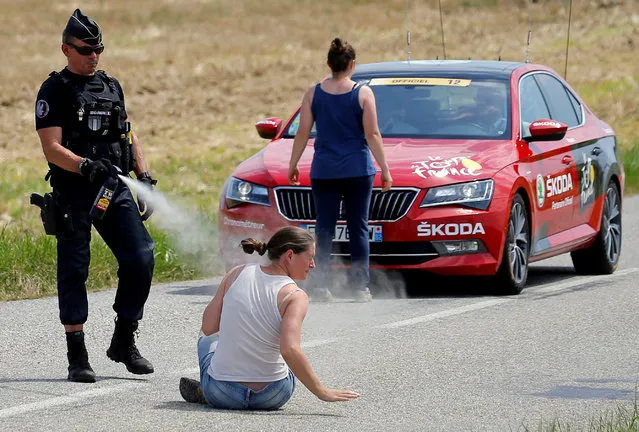 A police officer pepper sprays a protester as another protester stands in front of the race director's car during a farmers' protest who attempted to block the stage' s route, during the 16 th stage of the 105 th edition of the Tour de France cycling race, between Carcassonne and Bagneres- de- Luchon, southwestern France, on July 24, 2018. The race was halted for several minutes on July 24 after tear gas was used as protesting farmers attempted to block the route. (Photo by Stephane Mahe/Reuters)