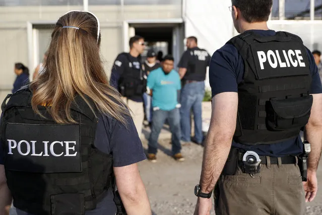 In this June 5, 2018 file picture, government agents detain suspects during an immigration raid in Castalia, Ohio. Regular raids are a key part of President Donald Trump's administration's crackdown on immigrants living in the U.S. illegally. (Photo by John Minchillo/AP Photo)