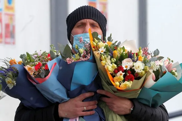 A man carries flowers at a market on International Women's Day in Moscow, Russia on March 8, 2021. (Photo by Evgenia Novozhenina/Reuters)