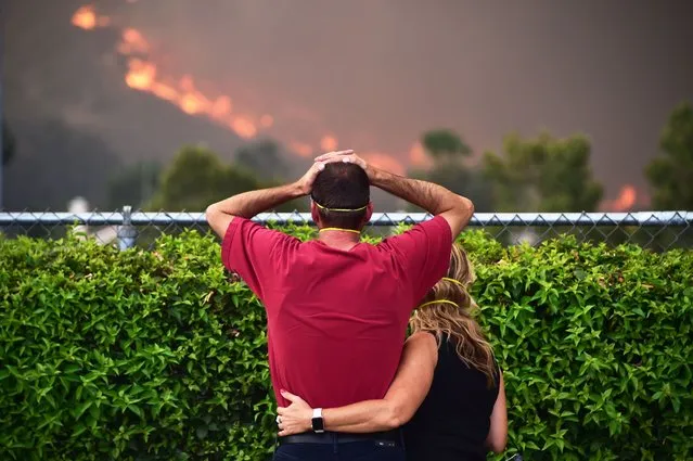 Ziggy Torok (L) and Starla Affatati watch with concern as flames close in on Torok's home in the Rice Canyon neighborhood as the Holy Fire burns in Lake Elsinore, California, southeast of Los Angeles, on August 9, 2018. A man suspected of intentionally starting the Holy Fire on August 6 in the nearby Cleveland National Forest was charged August 9 with multiple felony counts involving arson. (Photo by Robyn Beck/AFP Photo)
