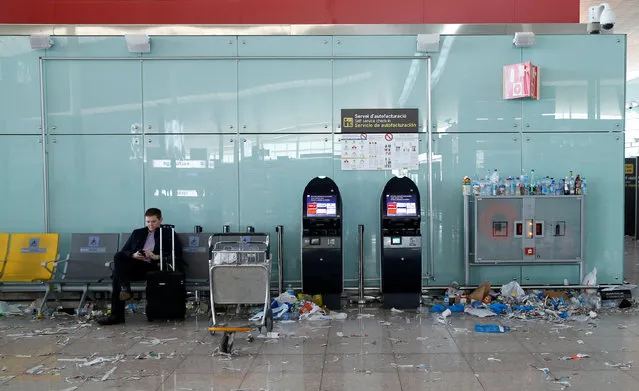 A passenger checks his mobile as garbage is accumulated during a protest by the cleaning staff at Barcelona's airport, Spain, December 1, 2016. (Photo by Albert Gea/Reuters)