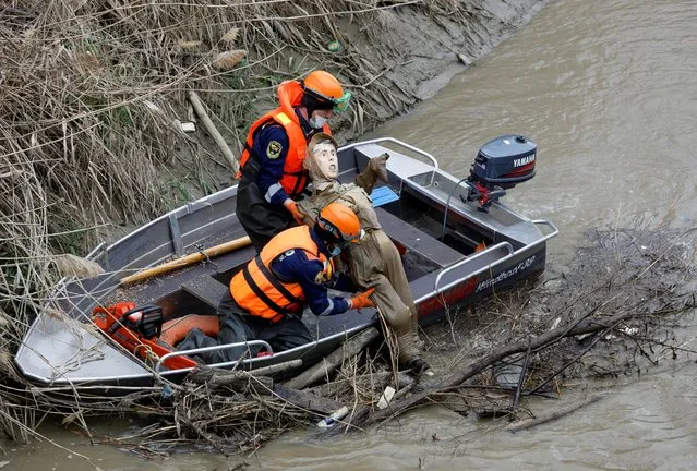 Rescuers remove a training dummy from a river during flood control exercises in the city of Svetlograd in Stavropol Region, Russia on April 14, 2021. (Photo by Eduard Korniyenko/Reuters)