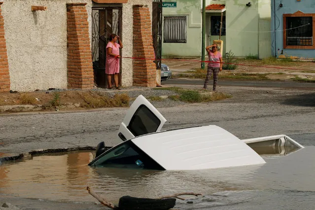 Women react near a pick-up truck submerged in a sinkhole at a street damaged by heavy rains in Ciudad Juarez, Mexico on September 6, 2018. (Photo by Jose Luis Gonzalez/Reuters)