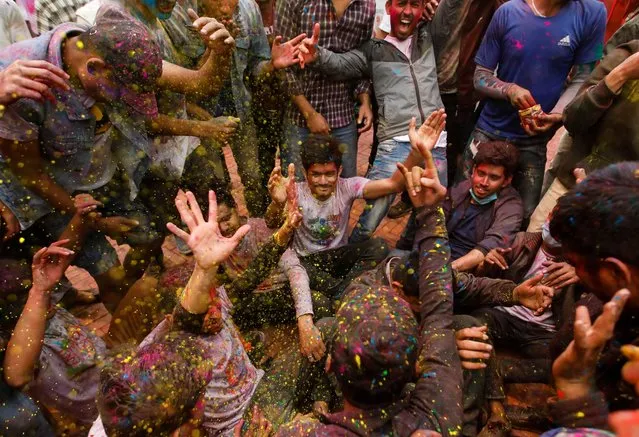 People throw coloured powder at each other as they gather to celebrate Holi in Kathmandu, Nepal on March 28, 2021. (Photo by Navesh Chitrakar/Reuters)