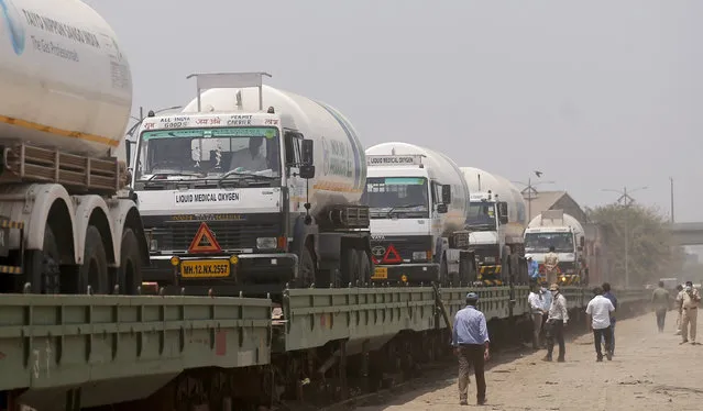 Empty tankers are loaded on a train wagon at the Kalamboli goods yard in Navi Mumbai, Maharashtra state, India, before they are transported to collect liquid medical oxygen from other states, Monday, April 19, 2021. The western Maharashtra state, which is worst hit by the coronavirus is facing a shortage of the gas used for the treatment of COVID-19 patients. India is being overrun by hundreds of thousands of new coronavirus cases, bringing a new reality for daily life in its main cities and towns. (Photo by Rafiq Maqbool/AP Photo)