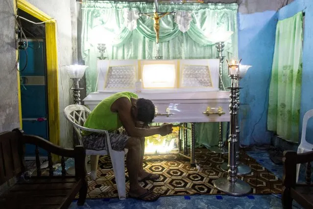 Marcel Dondoy mourns near the casket of his wife Joan Dondoy, who died in the capsized boat M/B Princess Aya, in Binangonan, Rizal province, Philippines on July 28, 2023. (Photo by Eloisa Lopez/Reuters)