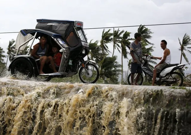 Filipino typhoon victims riding on a three-wheeled motorcycle maneuver on floodwater in the typhoon-hit town of Abulog, Cagayan province, Philippines, 20 October 2016. Many houses, trees, and electric posts were destroyed after Super Typhoon Heima made landfall in the Northern Philippines. (Photo by Francis R. Malasig/EPA)