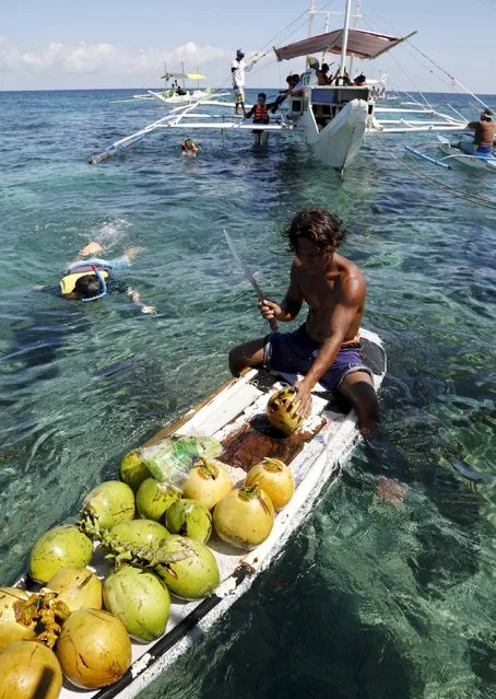 A vendor on his makeshift raft, chops a coconut to sell the juice to snorkelling tourists off the posh island of Boracay, central Philippines, January 18, 2016. (Photo by Charlie Saceda/Reuters)