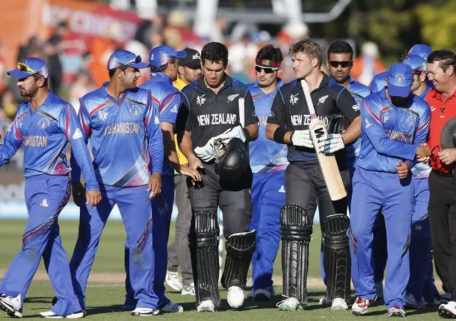 New Zealand's Ross Taylor (in black, L) and Cory Anderson leave the field with Afghanistan's players after their Cricket World Cup match in Napier, March 8, 2015. REUTERS/Nigel Marple (NEW ZEALAND)