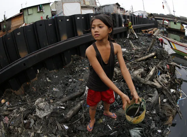 A Filipino girl collects useful materials next to a dike at an on-going flood control project in Paranaque city, south of Manila, Philippines, December 12, 2015. (Photo by Francis R. Malasig/EPA)