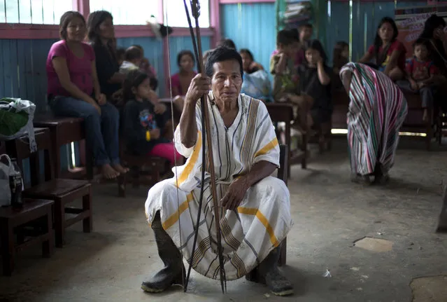 In this March 16, 2015 photo, Ashaninka Indian Guillermo Arevalo holds onto to his bow and arrow during a community meeting to discuss land titles and education, in the hamlet of Saweto, Peru. Saweto holds weekly meetings to discuss local issues, where all adults have the right to address the gathering. (Photo by Martin Mejia/AP Photo)