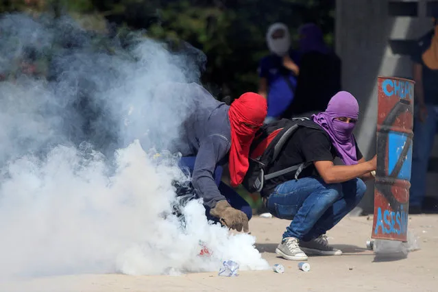 A demonstrator holds a tear gas canister fired by policemen during a protest against the government of Honduras' President Juan Orlando Hernandez outside the National Autonomous University of Honduras (UNAH) in Tegucigalpa, Honduras November 28, 2018. (Photo by Jorge Cabrera/Reuters)