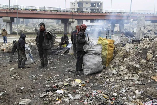 Scavengers carry bags after sifting through garbage from a rubbish dump in Aleppo January 21, 2015. (Photo by Jalal Al-Mamo/Reuters)