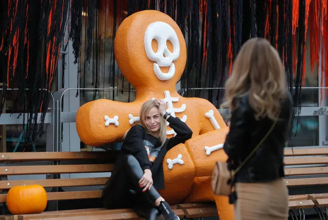 A young woman poses for photo near a cafe decorated for Halloween celebration in Kiev, Ukraine, 29 October 2020. Halloween celebrations, which are held annually on 31 October in many countries, become popular in Ukraine too. (Photo by Sergey Dolzhenko/EPA/EFE)
