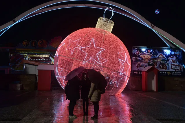 This picture taken on December 18, 2018, shows people standing in the entrance of International Fair decorated by a giant christmas ball in Thessaloniki, Greece, on December 18, 2018. (Photo by Sakis Mitrolidis/AFP Photo)