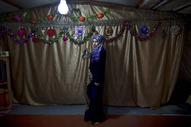 In this Tuesday, March 17, 2015 photo, pregnant Syrian refugee Huda Alsayil, 20, poses for a portrait inside her tent at an informal tented settlement near the Syrian border, on the outskirts of Mafraq, Jordan. “A couple of weeks ago, I couldn't feel my baby moving in my belly so I panicked and didn't know what to do since I can't afford heading to a clinic and check”, says Alsayil, who fled fighting in Hama three years ago and is five months pregnant. (Photo by Muhammed Muheisen/AP Photo)
