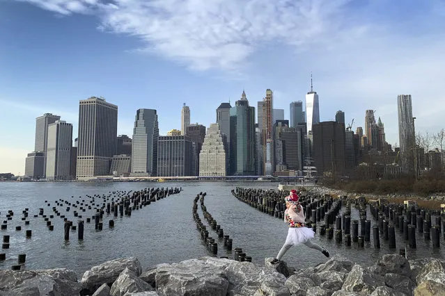 With downtown Manhattan in the background, a girl leaps across boulders forming a breakwater along the Brooklyn Bridge Park on Thursday December 27, 2018, in the Brooklyn borough of New York. (Photo by Wong Maye-E/AP Photo)