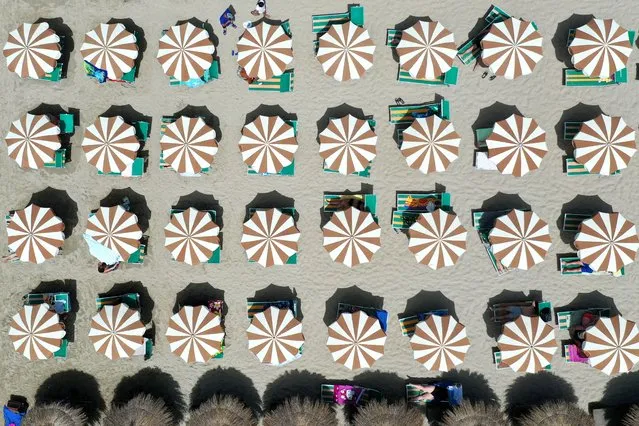 This aerial view taken in Durres on June 25, 2021, shows beach umbrellas lined up on the beach. The heat wave hit Albania where temperatures reach a peak of 42 degrees Celsius. (Photo by Gent Shkullaku/AFP Photo)