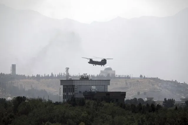 A U.S. Chinook helicopter flies over the U.S. Embassy in Kabul, Afghanistan, Sunday, August 15, 2021. Helicopters are landing at the U.S. Embassy in Kabul as diplomatic vehicles leave the compound amid the Taliban advanced on the Afghan capital. (Photo by Rahmat Gul/AP Photo)