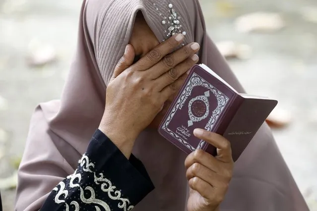 An Acehnese woman prays and reads the Koran at a mass grave for tsunami victims, in rememberance of their deceased family members during the 2004 Tsunami Commemoration in Banda Aceh, Indonesia, 26 December 2023. On 26 December 2023, Indonesia marks the 19th anniversary of the 2004 tsunami which was triggered by a 9.2 earthquake in the Indian Ocean off the west coast of northern Sumatra, and killed an estimated 230,000 people in 14 countries. (Photo by Hotli Simanjuntak/EPA)