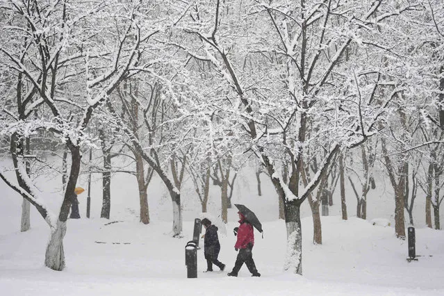 People walk through the snow in Goyang, South Korea, Saturday, December 30, 2023. South Korean Meteorological Administration issued a heavy snow advisory for some parts of the Korea peninsula. (Photo by Lee Jin-man/AP Photo)