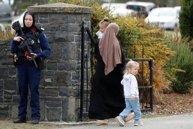 A policewoman is seen as people attend the burial ceremony of a victim of the mosque attacks, at the Memorial Park Cemetery in Christchurch, New Zealand March 21, 2019. (Photo by Jorge Silva/Reuters)
