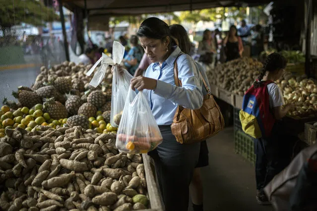 In this February 14, 2019 photo, Carmen Victoria Gimenez, 43, shops at a farmers market in the middle-class district of Los Dos Caminos, in Caracas, Venezuela. “I earn much more than the minimum wage and I still struggle”, she said. “I can't even imagine how the poorest of the poor survive”. (Photo by Rodrigo Abd/AP Photo)