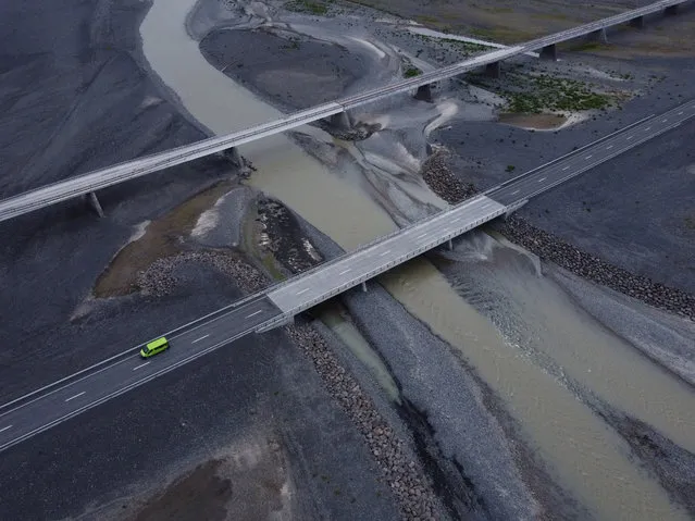 In this aerial view, cars driving on Iceland's ring road, Route 1, cross a small bridge over a river next to a much longer, abandoned bridge on the Skeidararsandur plain on August 18, 2021 near Skaftafell, Iceland. The longer bridge, originally built in the 1970s, crossed the then wide Skeidara river. However, in 2009, due to the retreat of nearby glaciers that feed the Skeidara, the river changed it course, leaving a much diminished flow at the previous location and making the longer bridge superfluous. Iceland is feeling a strong impact from global warming. Since the 1990s 90% of Iceland's glaciers have been retreating and projections for the future show a continued and strong reduction in size of its ice caps. (Photo by Sean Gallup/Getty Images)