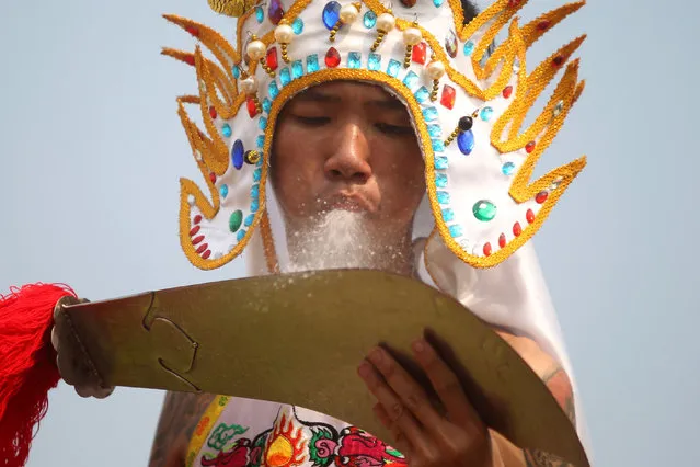 A worshipper spits water on a sword as he takes part in Hei Neak Ta, or procession of the spirits which marks the end of the celebration of the Lunar New Year for the Chinese community in Phnom Penh, Cambodia, February 10, 2017. (Photo by Samrang Pring/Reuters)