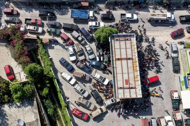 Cars line up as people wait with motorcycles and plastic containers at a gas station amid a nationwide shortage of fuel, in Port-au-Prince, Haiti on October 31, 2021. (Photo by Ralph Tedy Erol/Reuters)
