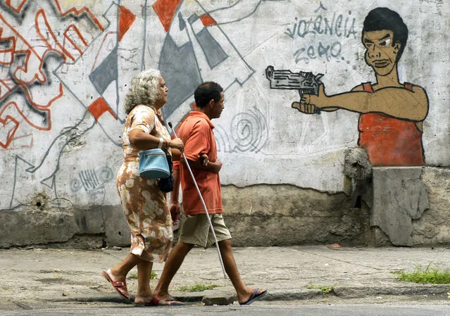 In this October 22, 2005 file photo, people walk past graffiti in Rio de Janeiro, Brazil, a day before a vote to ban the sale of firearms and ammunition to civilians. Backed by the Roman Catholic church and other powerful forces in the country, one poll a month before the referendum put support at 73 percent. The U.S.-based National Rifle Association worked with activists in Brazil to help defeat it. (Photo by Renzo Gostoli/AP Photo/File)