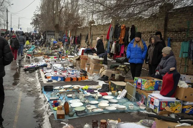 People sell objects at a city flea market in Ukraine's capital Kyiv,  Sunday, February 11, 2024. Despite more and more buyers having to tighten their belts, the market still offers a large variety of goods as it survived the second year of war with Russia. (Photo by Efrem Lukatsky/AP Photo)