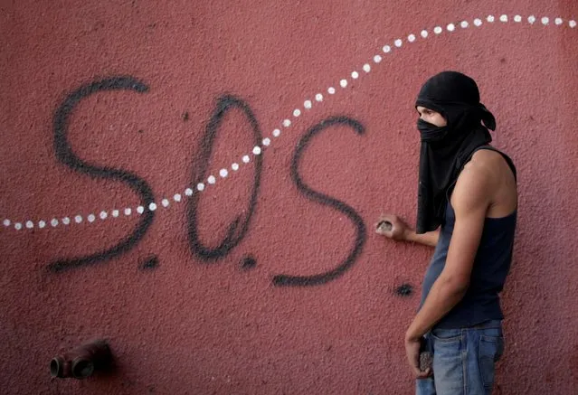 An opposition supporter holds rocks during clashes with security forces following a rally against the government of Venezuela's President Nicolas Maduro and to commemorate May Day in Caracas, May 1, 2019. (Photo by Ueslei Marcelino/Reuters)