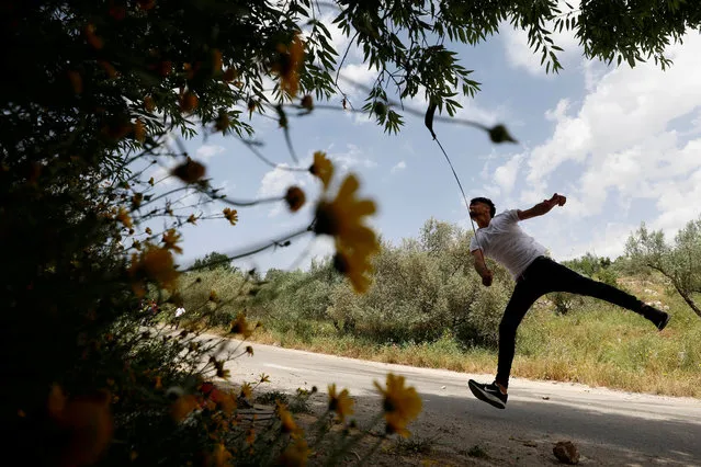 A Palestinian hurls stones at Israeli troops during clashes at a protest against Jewish settlements, near Ramallah in the Israeli-occupied West Bank on May 3, 2019. (Photo by Mohamad Torokman/Reuters)