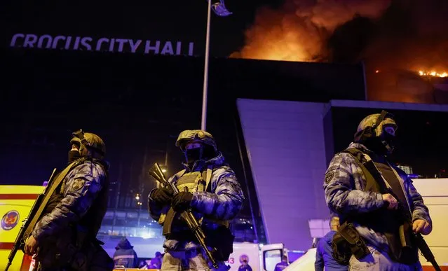Russian law enforcement officers stand guard near the burning Crocus City Hall concert venue following a reported shooting incident, outside Moscow, Russia, on March 22, 2024. (Photo by Maxim Shemetov/Reuters)