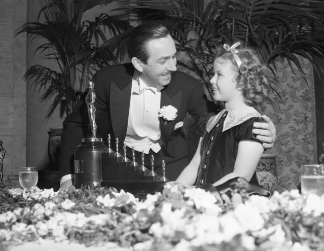Shirley Temple presents an Academy Award to Walt Disney for his outstanding cartoon, “Snow White and the Seven Dwarfs”, one big statue and seven little ones, at the 11th Annual Academy of Motion picture Arts & Sciences dinner in Los Angeles, CA, 1939. (Photo by Bettmann/Getty Images)