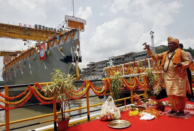 A Hindu priest performs a ritual to give blessings to Kavaratti, an anti-submarine warfare corvette for the Indian Navy built by Garden Reach Shipbuilders & Engineers Ltd. (GRSE), a warship manufacturing company, during its launch at a dockyard in Kolkata, India, May 19, 2015. (Photo by Rupak De Chowdhuri/Reuters)