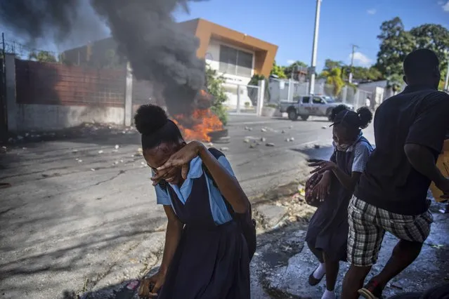 Students run past a burning barricade set up by protesters demanding the release of kidnapped people, in Port-au-Prince, Haiti, Thursday, November 25, 2021. The country is experiencing a rise in gang-related kidnappings, many demanding ransom, with the U.S. State Department issuing a warning in Aug. about the risk of kidnapping in Caribbean country. (Photo by Joseph Odelyn/AP Photo)
