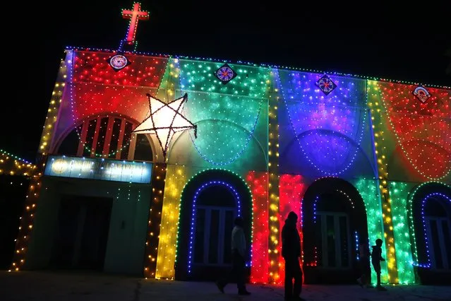 People walk past an illuminated church ahead of Christmas in Ahmedabad, India, Wednesday, December 22, 2021. (Photo by Ajit Solanki/AP Photo)