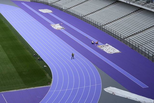 A worker crosses the track as preparations continue at the Stade de France ahead of the Paris Olympics, Tuesday, May 7, 2024, in Paris. The Paris Olympic games are set to begin in late July. (Photo by David J. Phillip/AP Photo)