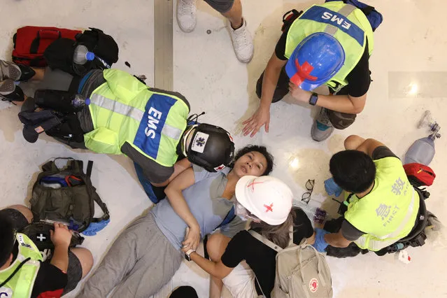 An injured woman lies on the ground accepting the treat in a shopping mall while anti-extradition bill protesters march during a rally in Shatin, Hong Kong, China, 14 July 2019. (Photo by Jerome Favre/EPA/EFE)