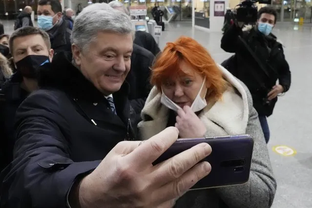 Former Ukrainian President Petro Poroshenko, left, poses for a selfie with a Ukrainian supporter at Warsaw's international airport before boarding a flight to Kyiv, Ukraine, on Monday, January 17, 2022. Poroshenko is returning to Ukraine to fight treason charges which he views as politically motivated. (Photo by Czarek Sokolowski/AP Photo)